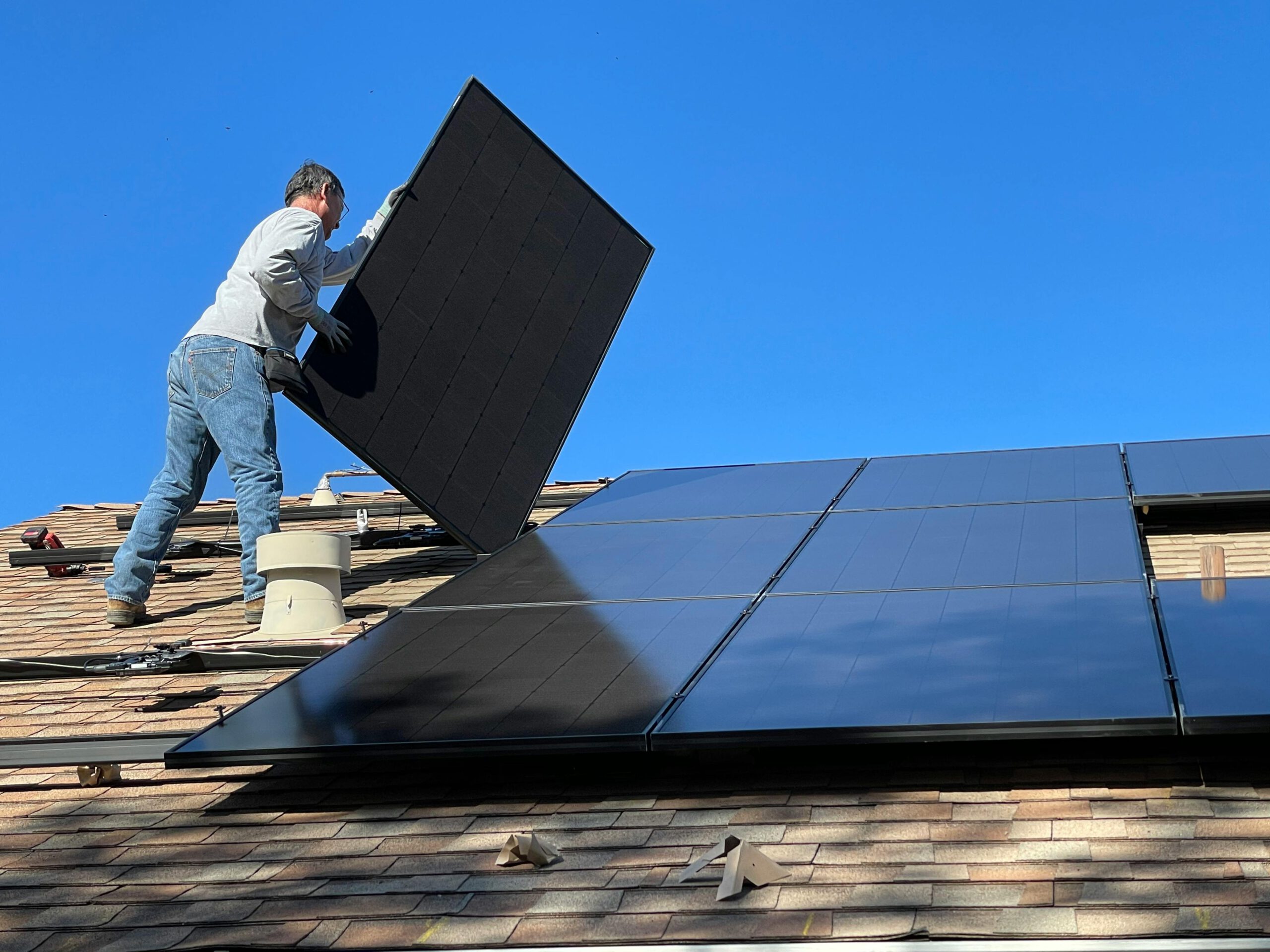 A worker installs solar panels on a sunny day, highlighting renewable energy solutions.
